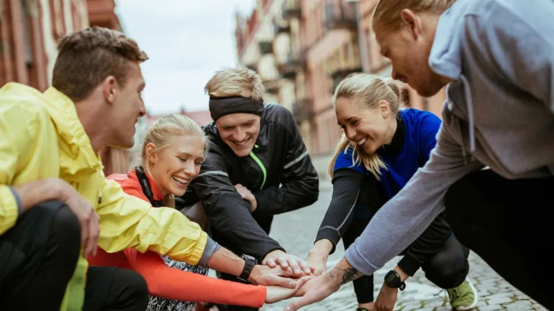 A group of runners squatting with their hands in a circle