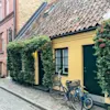 Ett gammalt, litet, gult hus i Malmö med två cyklar utanför.