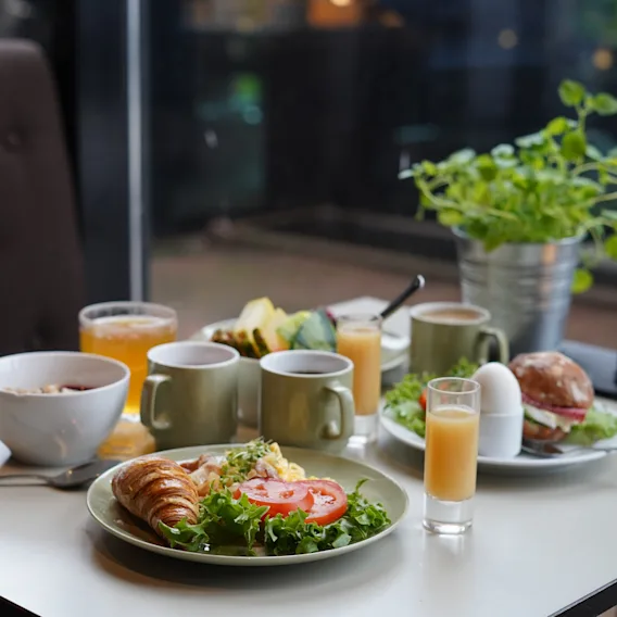 En härlig hotellfrukost dukad på ett bord med kaffe, juice, färska grönsaker och croissanter.