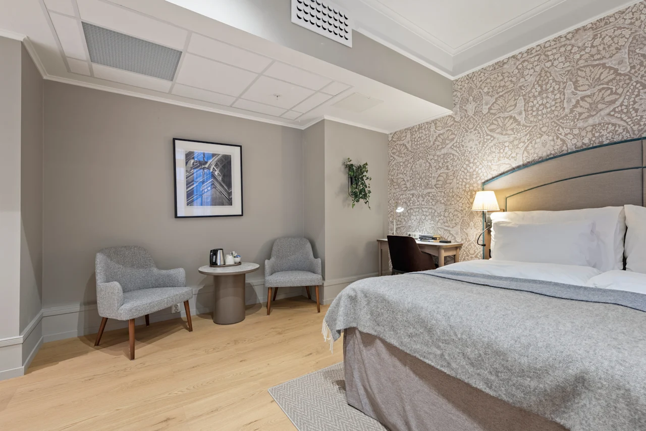 A cozy hotel room with a comfortable bed, a functional desk, and a relaxing seating area for guests.