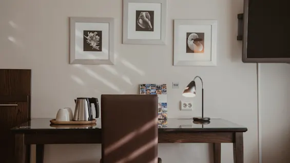 En mysig skrivbordsplats i ett rum, med vattenkokare, koppar och lampa, snäckkonst på väggen och rumsnummer 502.
