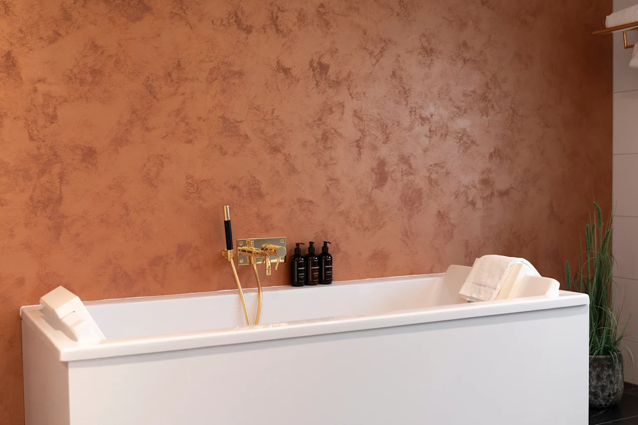 A welcoming bathroom at Home Hotel Grand Bodø, showcasing a clean white bathtub with stylish golden taps and bath products.