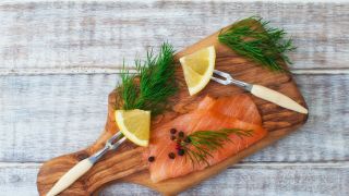 Cured salmon with dill and lemon on a wooden cutting board.