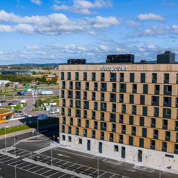 En rektangulär byggnad med flera våningar märkt "Söderöver" står mot en bakgrund av ett förortsområde. I närheten syns en "Max"-snabbmatsrestaurang längs ett gatunät.