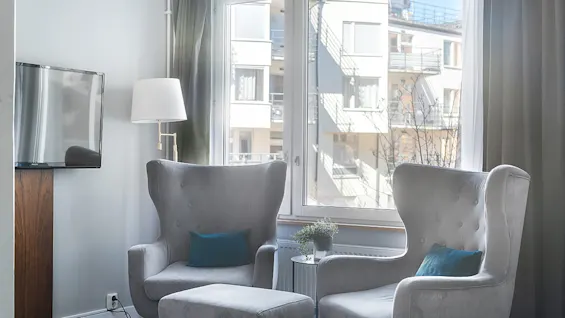 Two grey wingback chairs with blue cushions in a bright living room facing a window with daylight.