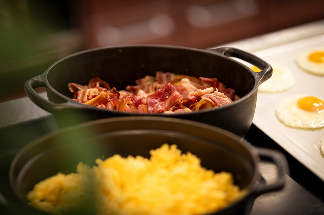 A delicious breakfast buffet featuring crispy bacon, fluffy scrambled eggs, and perfectly fried eggs ready to be served.