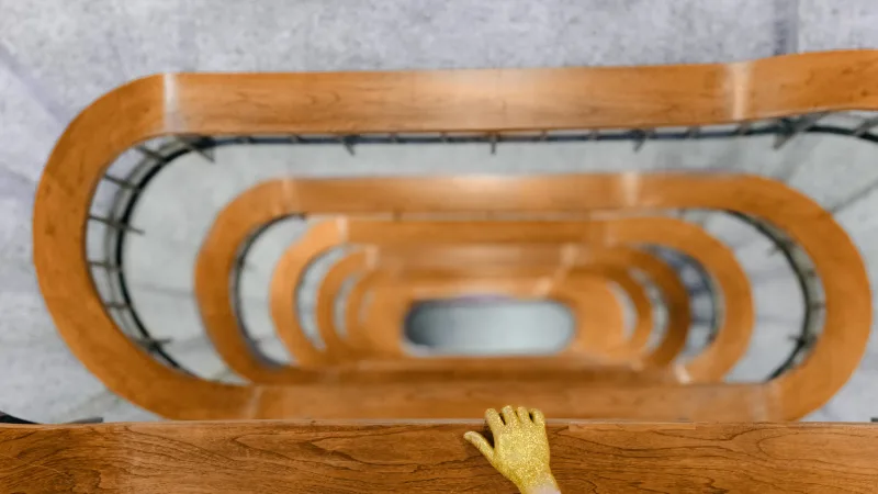 En gullhånd som holder på et trapperekkverk