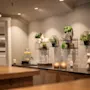 Glaskander indeholder citronvand på en moderne disk, omgivet af potteplanter og varm ambient belysning. En dekorativ skulptur og stearinlys forbedrer den hyggelige, moderne lounge.