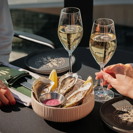 To personer nyder friske østers og mousserende vin på Restaurant NOR på Clarion Hotel Helsinki Airport.