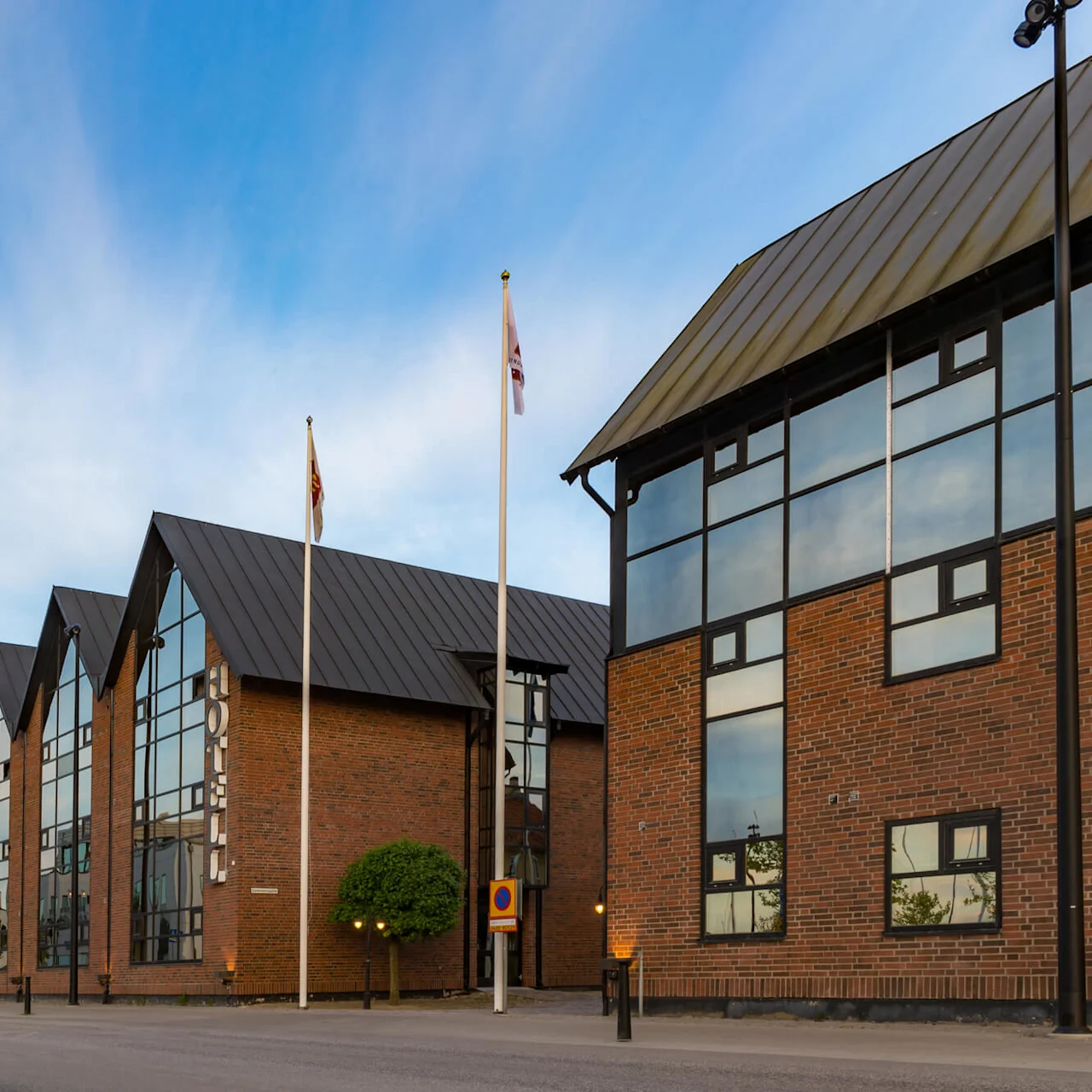A modern building with large windows under a clear sky, adjacent to a street with a Coast Guard ship visible in the background.