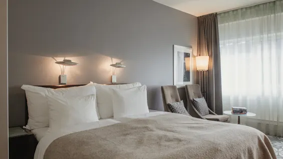 Ett mysigt hotellrum med en stor säng, två fåtöljer och mjuk belysning, som inbjuder till avkoppling.