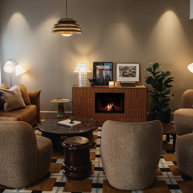 En varm och inbjudande lounge med en tänd öppen spis, bekväma sittplatser och mjuk belysning, perfekt för avkoppling.