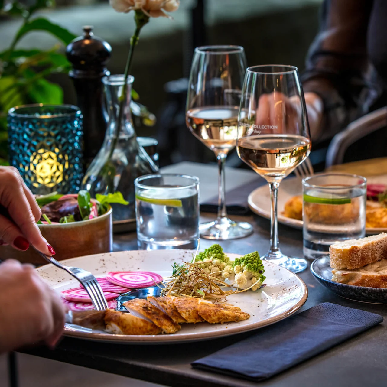 Two people dining at a table with wine, food, and an ambient candle.