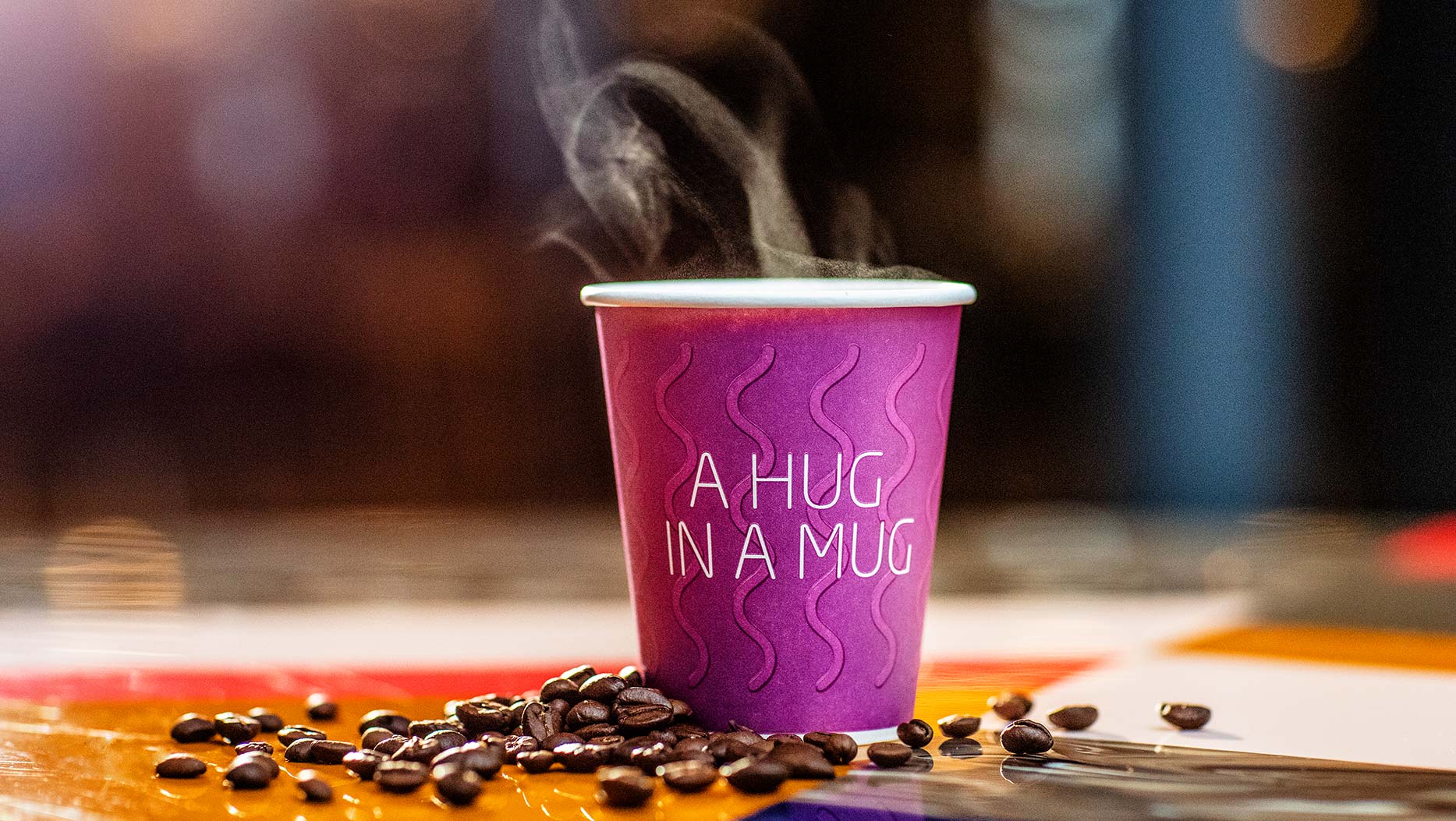 A paper cup of warm coffee with the text "A hug in a mug". 