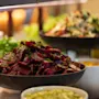 Ett färgstarkt bufféutbud, med en framträdande skål med skivade rödbetor och färska gröna örter, tillsammans med andra hälsosamma salladsalternativ.