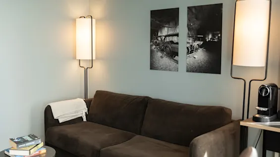 Et varmt og innbydende oppholdsrom med en myk brun sofa, stilige gulvlamper og fengslende svart-hvitt kunst.