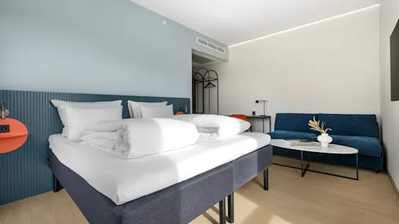 Et moderne og innbydende hotellrom med en komfortabel seng og en koselig sittegruppe.
