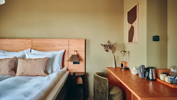 Et koselig hotellrom med en komfortabel seng og et funksjonelt skrivebordsområde, med varm belysning og moderne innredning.