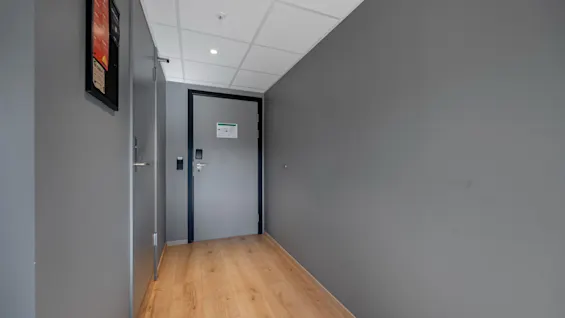 En moderne hotellkorridor på Comfort Hotel Porsgrunn med grå vegger, tregulv og en dør med kortleser.