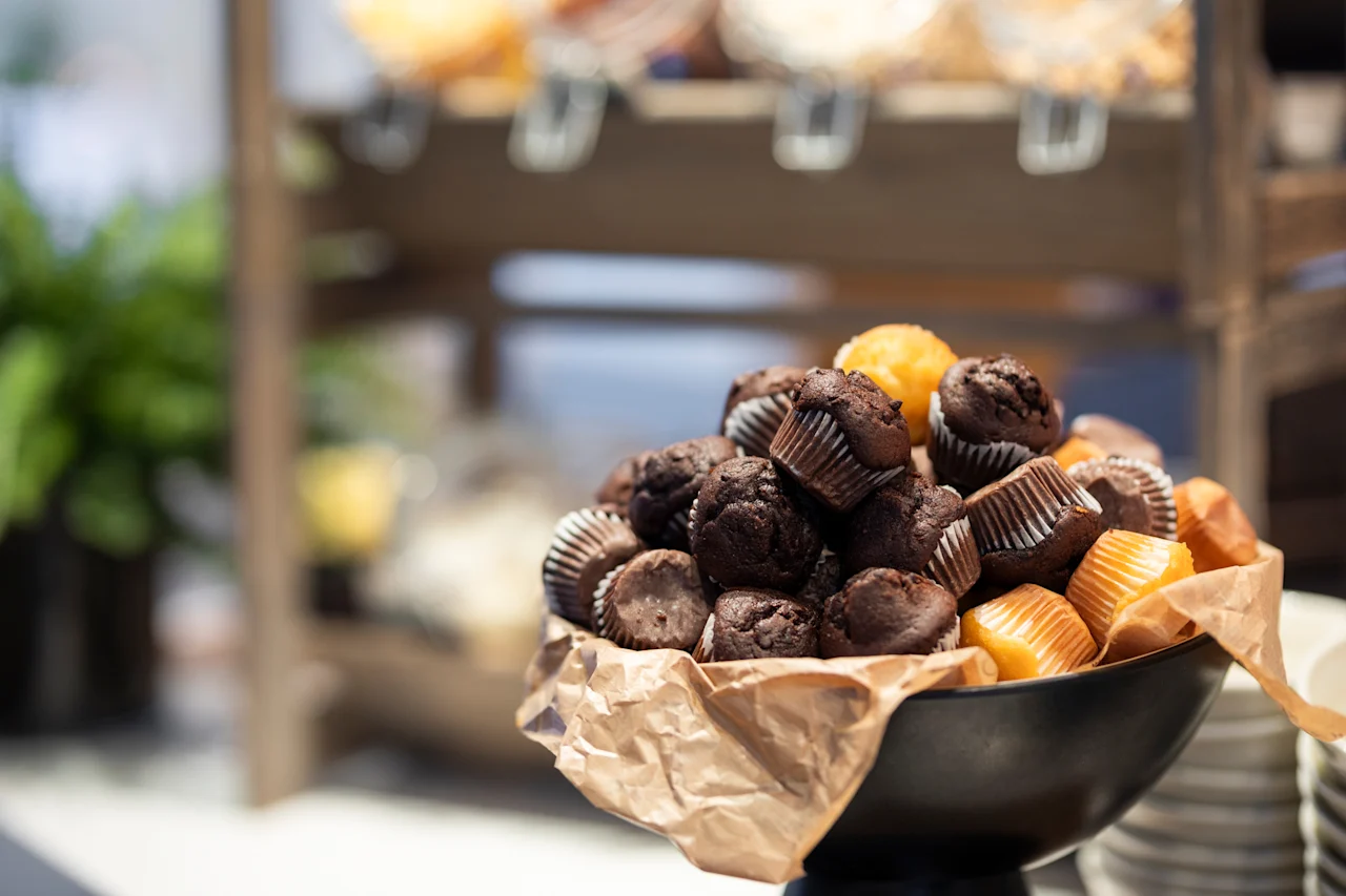 Kulho täynnä herkullisia suklaa- ja vaniljamuffinsseja, valmiina nautittavaksi buffetissa.