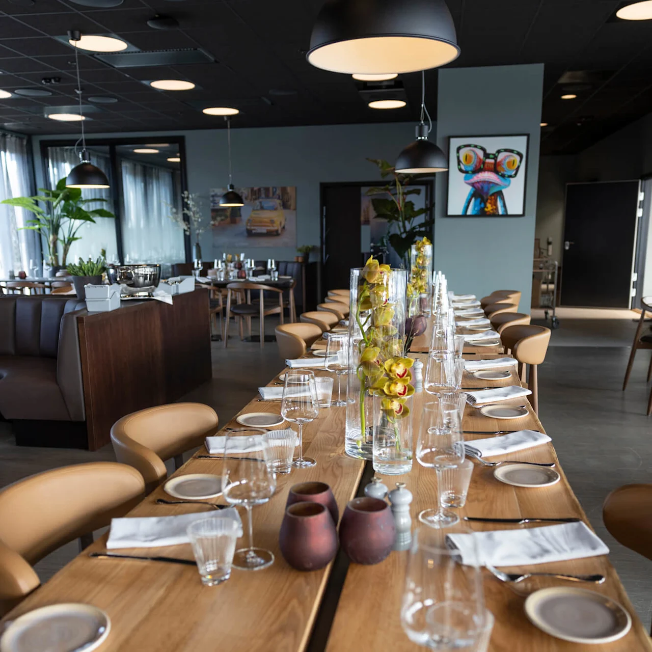 A long table set for dining with glasses and flowers in a modern restaurant interior. 
