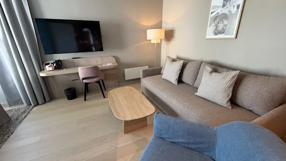 A cozy and modern living space with a comfortable sofa, a TV area, and a workspace, designed for relaxation and productivity.
