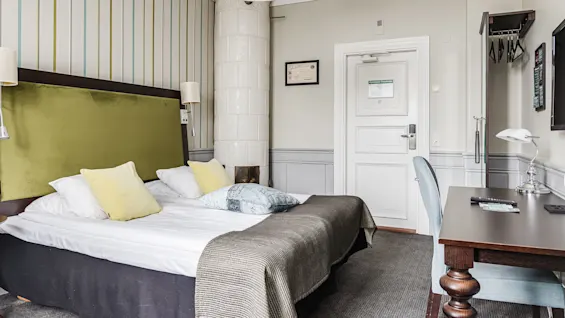 Bed in a neatly organized hotel room with contemporary design, striped wallpaper, and no people.