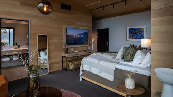 Ett modernt hotellrum med en bekväm säng, en stor TV och ett öppet badrum, som erbjuder en avkopplande och lyxig vistelse.