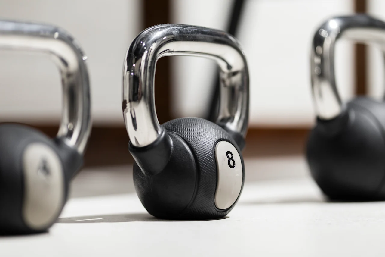 A close-up of several kettlebells on a gym floor, with one prominently displaying the number 8, ready for a workout.