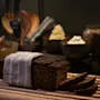 A delicious loaf of dark bread, partially sliced, on a wooden board at Home Hotel Kung Oscar, ready for a meal.