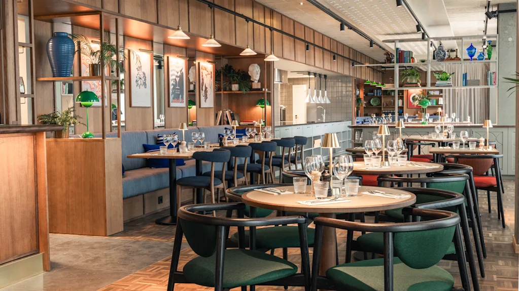 Et innbydende og moderne restaurantinteriør med flere bord dekket for bespisning, komfortable sitteplasser og elegant innredning.
