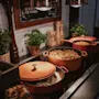 A buffet line with hot food in pots, fresh herbs, and a sign encouraging guests to "BE HERE NOT ON THE PHONES".
