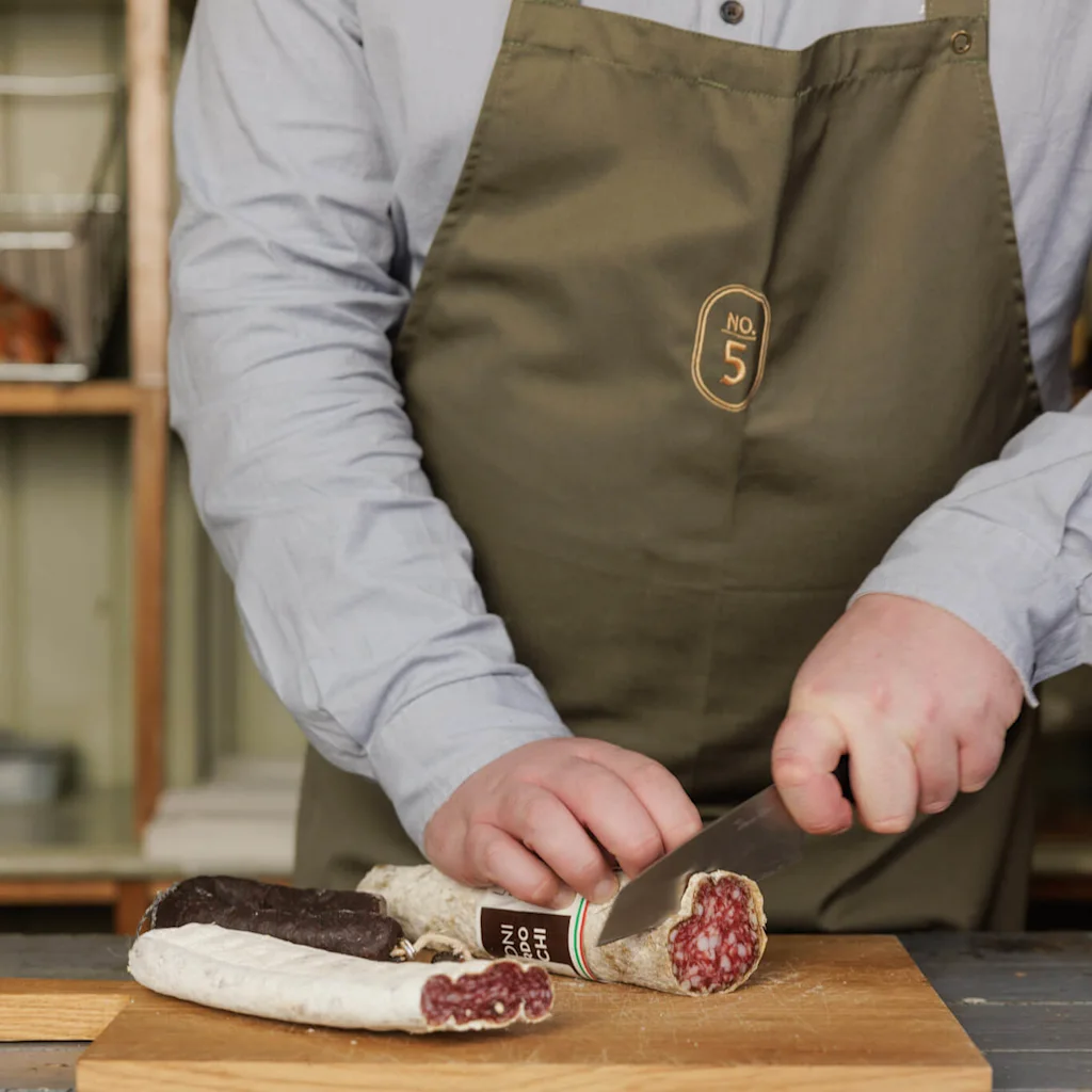 Chef cutting up charcuterie at restaurant Apotekergata No. 5.