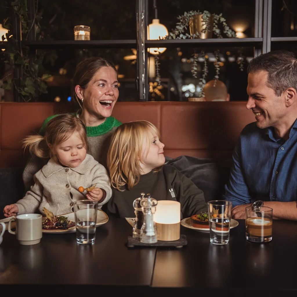 En familie som ler og koser seg med en hyggelig middag sammen på Quality Hotel™.