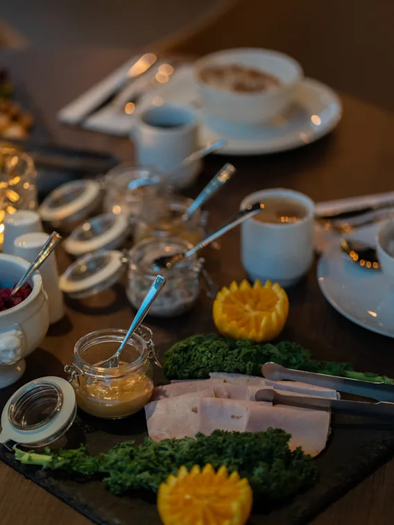 En vackert arrangerad frukostbuffé med skivad skinka, ett urval av sylt och färska apelsingarnityr.