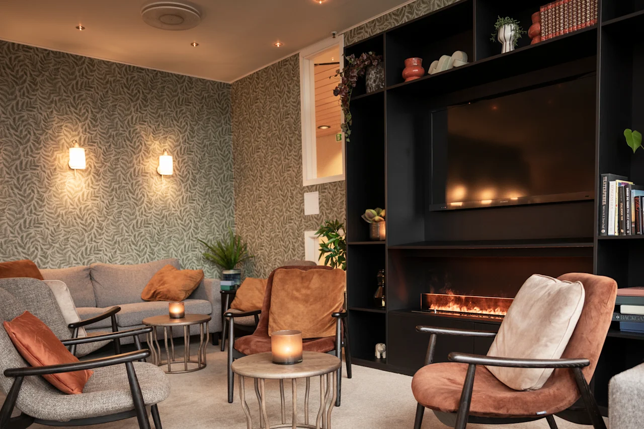 Viihtyisä oleskelutila mukavilla istuimilla, televisiolla ja takalla, luoden lämpimän ja kutsuvan tunnelman.