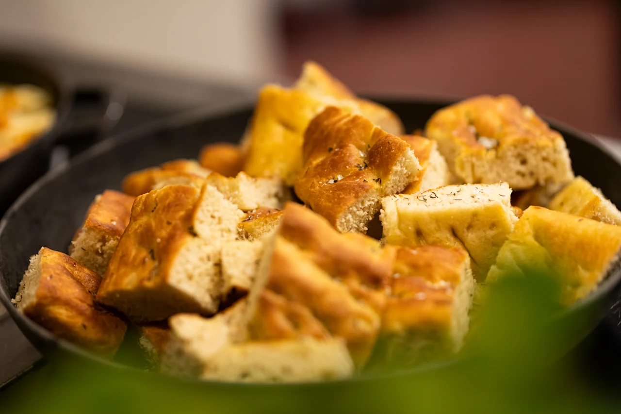 A bowl filled with freshly baked focaccia bread pieces, seasoned with herbs and sea salt, ready to be served.
