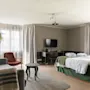 Kutsuva hotellihuone, jossa on mukava sänky, viihtyisä oleskelualue ja toimiva työpiste valoisan ikkunan äärellä.