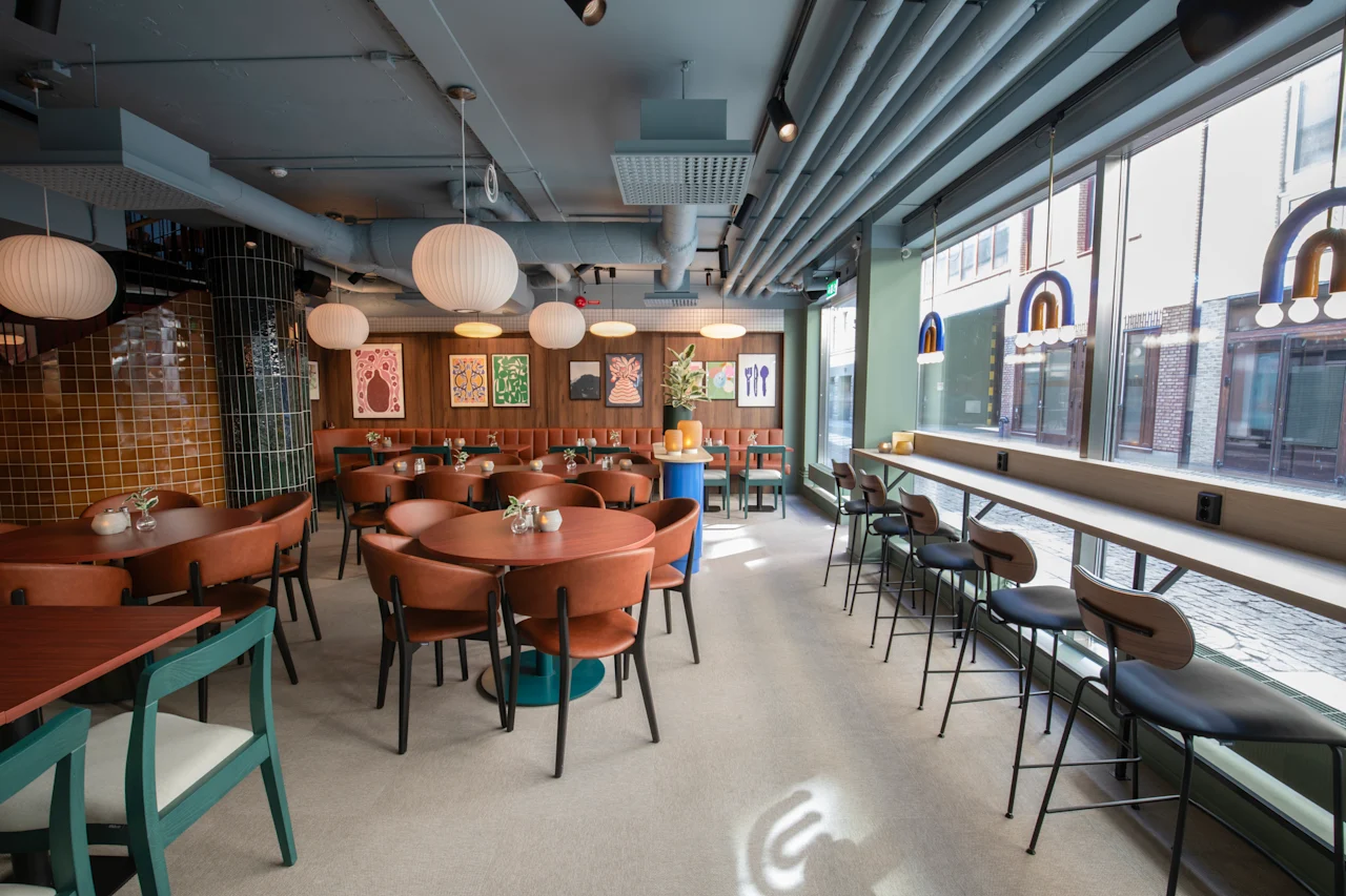 Comfort Hotel City Göteborg. Et moderne restaurantinteriør med runde borde, komfortable stole og et lyst vinduesbarområde.