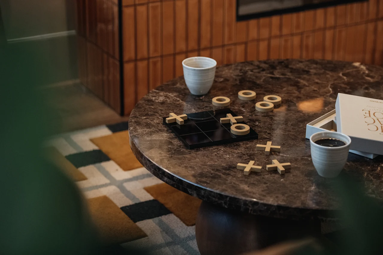 En mysig scen med ett luffarschackspel och två koppar på ett marmorbord, som inbjuder till en stunds lek och avkoppling.