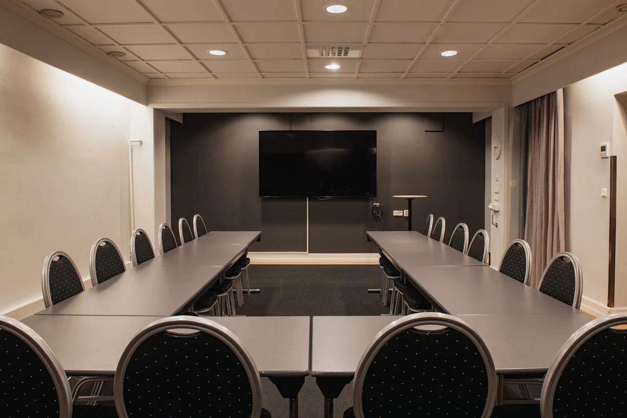 Ett modernt konferensrum med U-formad bordsuppställning och en stor skärm för presentationer på Home Hotel Grand, Helsingborg.