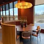 Et koselig, moderne spiseområde med et rundt bord, komfortable sitteplasser og et varmt lys fra en unik sirkulær lysarmatur.