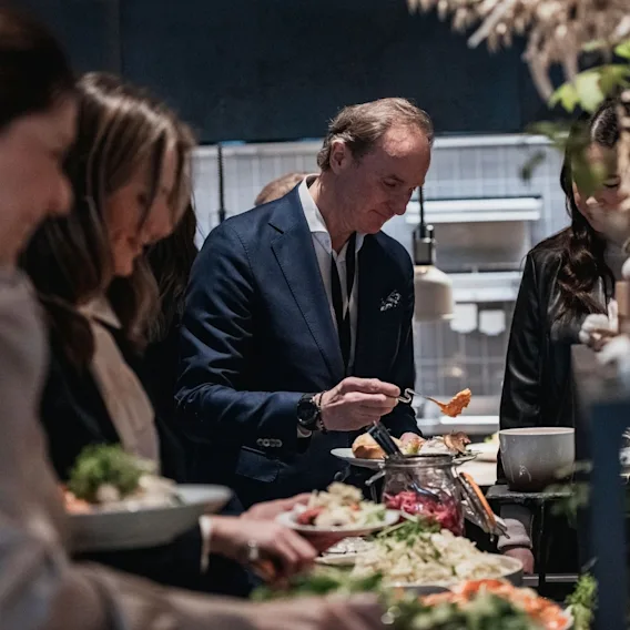Gjester i pyntet antrekk som forsyner seg fra et koldtbord under et selskap.