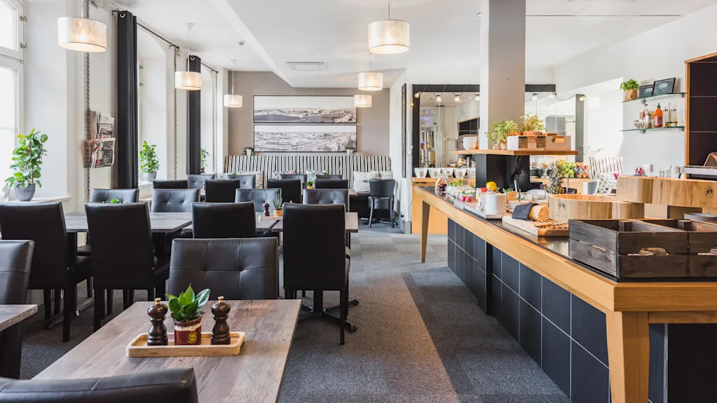 An empty restaurant interior with tables, chairs, and a buffet setup, ready to serve.
