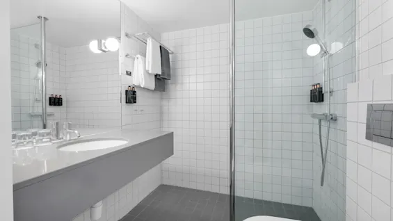 Et lyst, moderne hotellbad med romslig servant, dusj og toalett, for et rent og forfriskende rom.