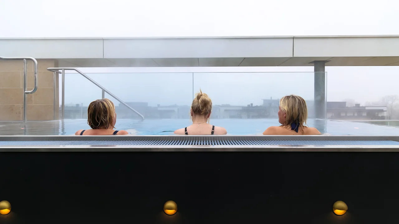 Tre personer slapper av i det varme vannet på Quality Hotel Öresund – Rooftop Spa og nyter utsikten.
