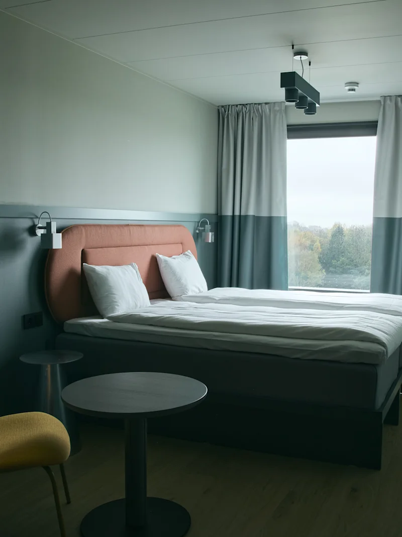 Ett modernt och inbjudande hotellrum på Stopover Hotel Falkenberg, med en bekväm säng och ljus fönsterutsikt.