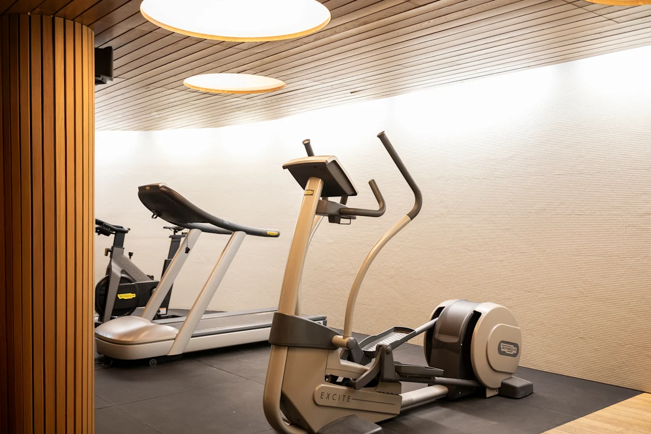 Ett modernt gym med en crosstrainer märkt EXCITE och ett löpband, redo för ett träningspass.
