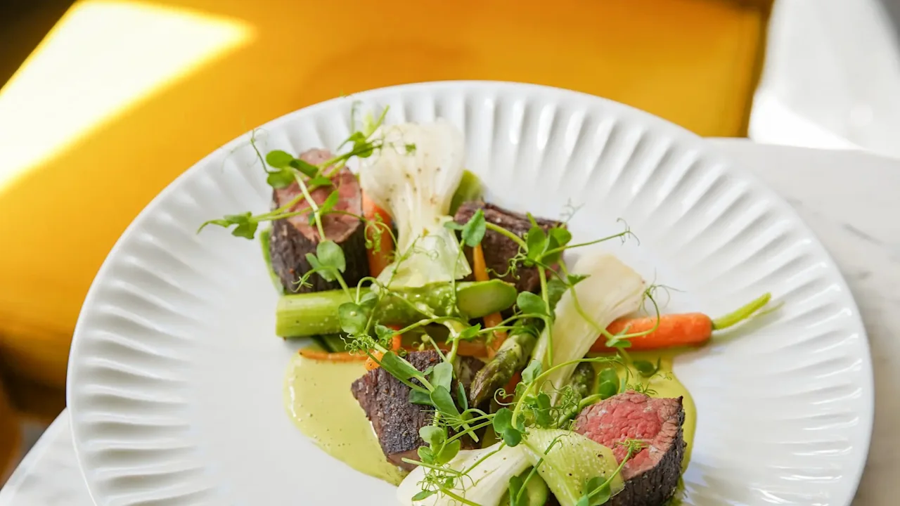 En fint anrettet rett med kjøtt og grønnsaker, ledsaget av en grønn saus, servert på Jørgensens Hotel – Restaurant Eydes.