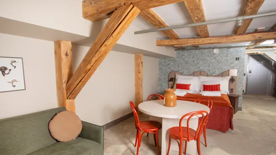 Juniorsuite at Home Hotel Bryggeparken, made bed with red pillows table, chairs and sofa